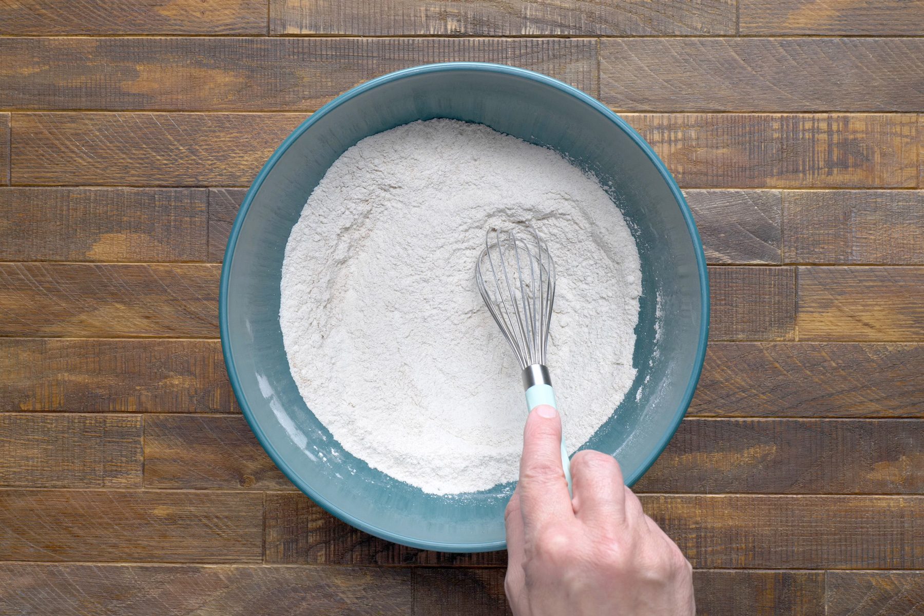 A hand using a whisk to mix dry ingredients