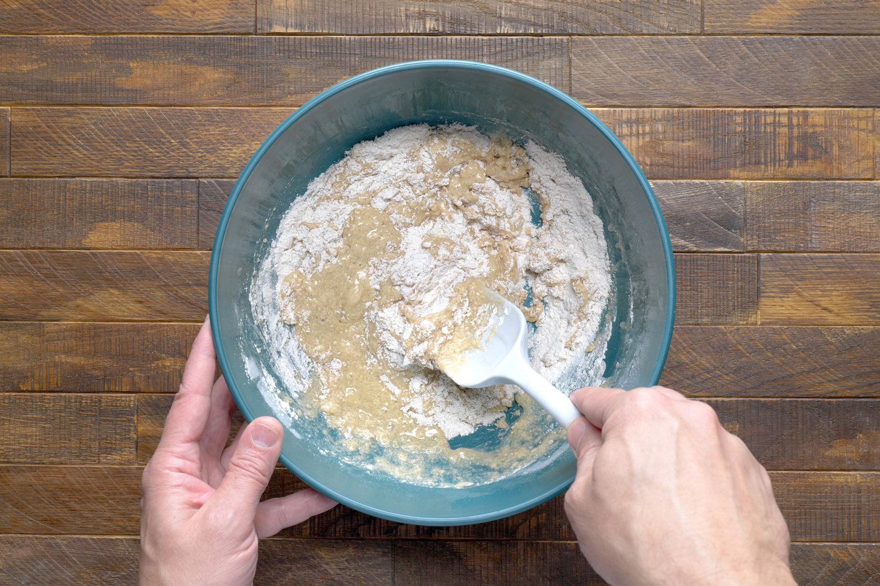 A hand stirring mixture with a spatula