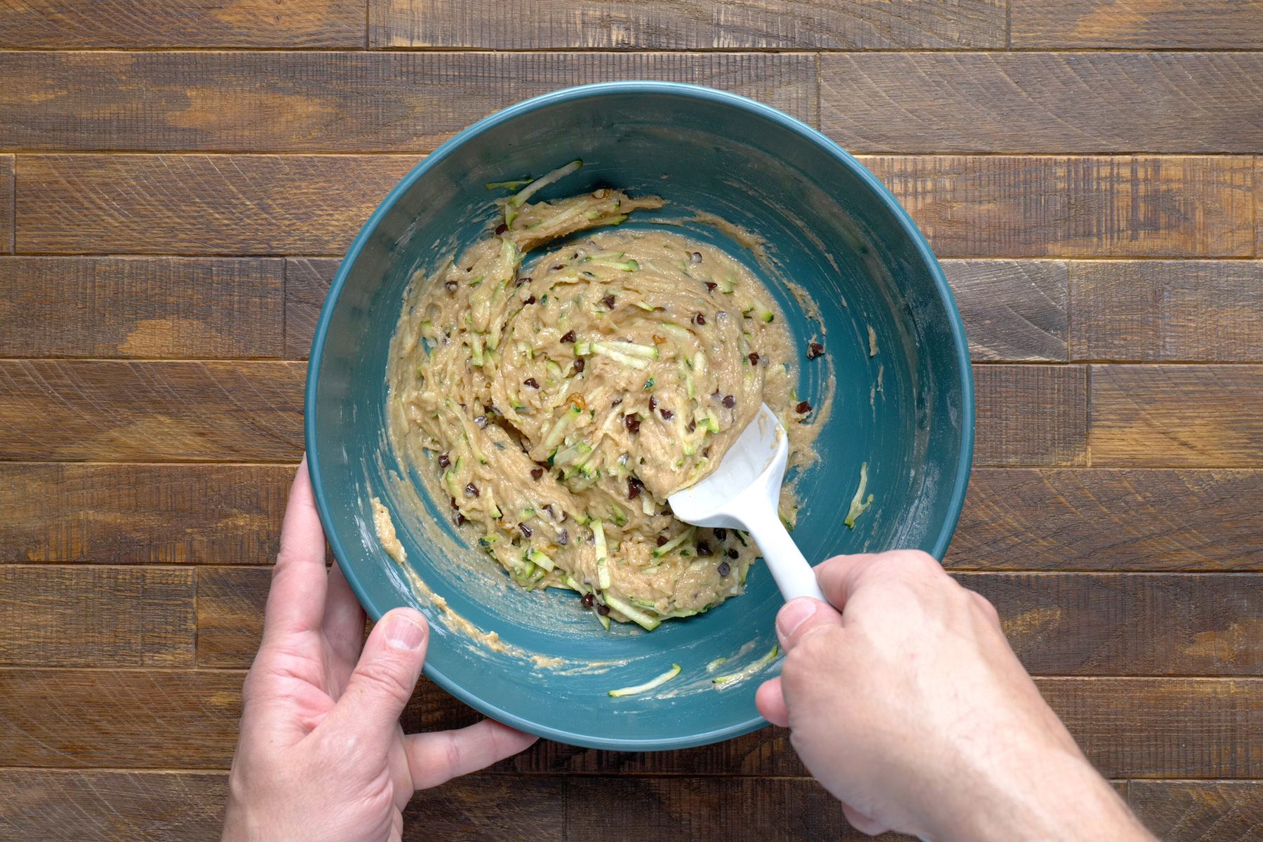 A hand stirring mixture with a spatula