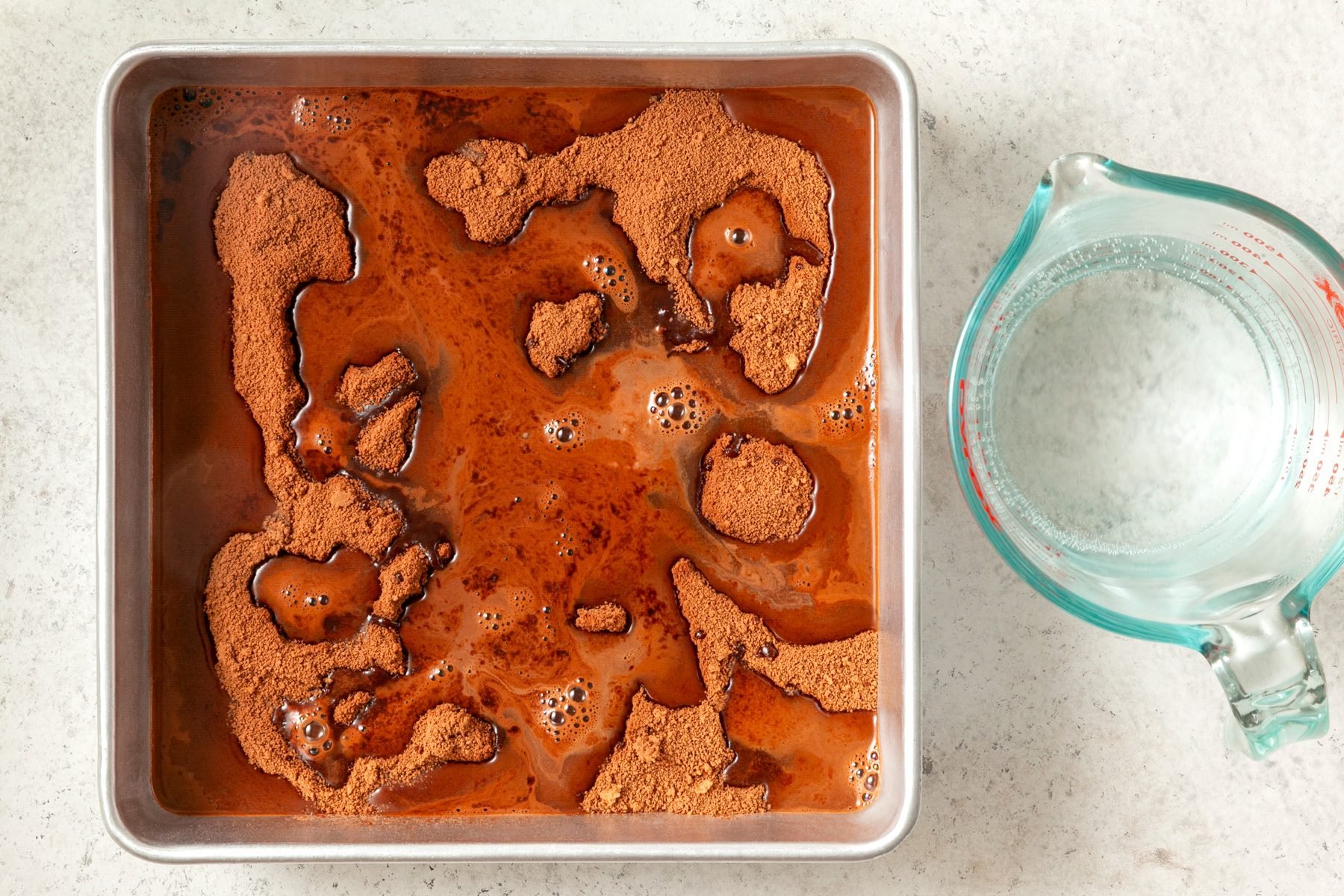 A baking pan filled with chocolate batter and water poured over it