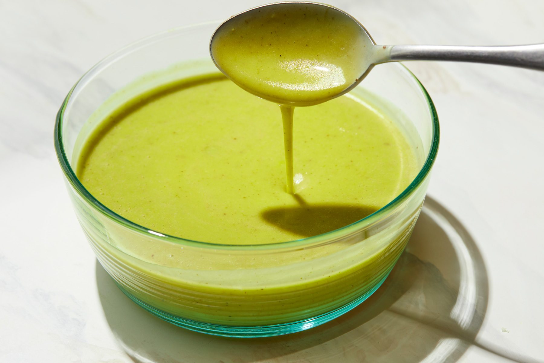 A glass bowl of Cilantro Lime Dressing with a spoon