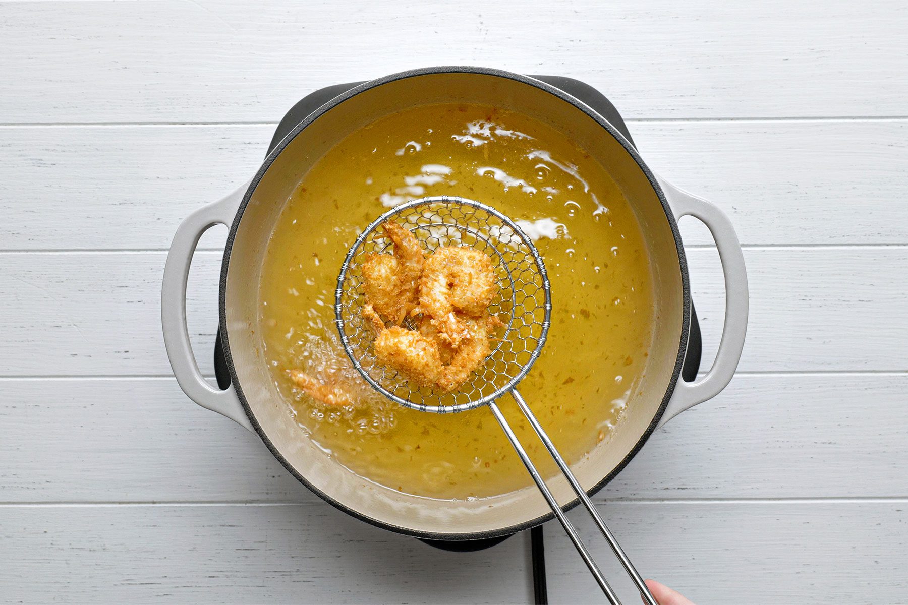 Overhead shot of fry shrimp in batches until golden brown; 3-4 minutes; white wooden background;