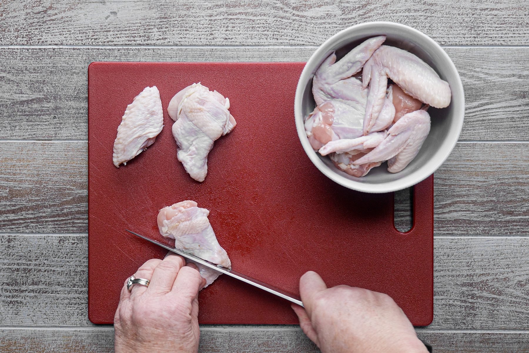 A person cutting chicken wings 