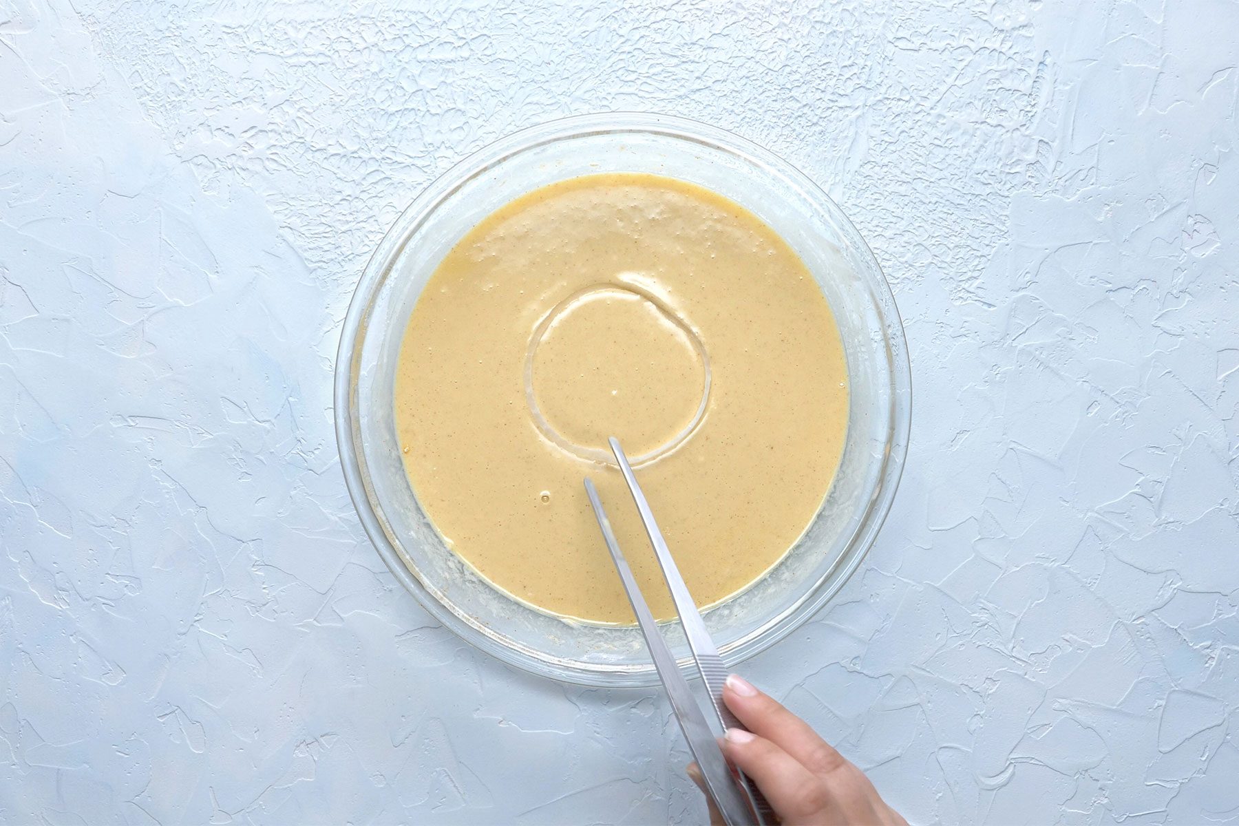 overhead shot; white textured background; Dipping rings into batter;