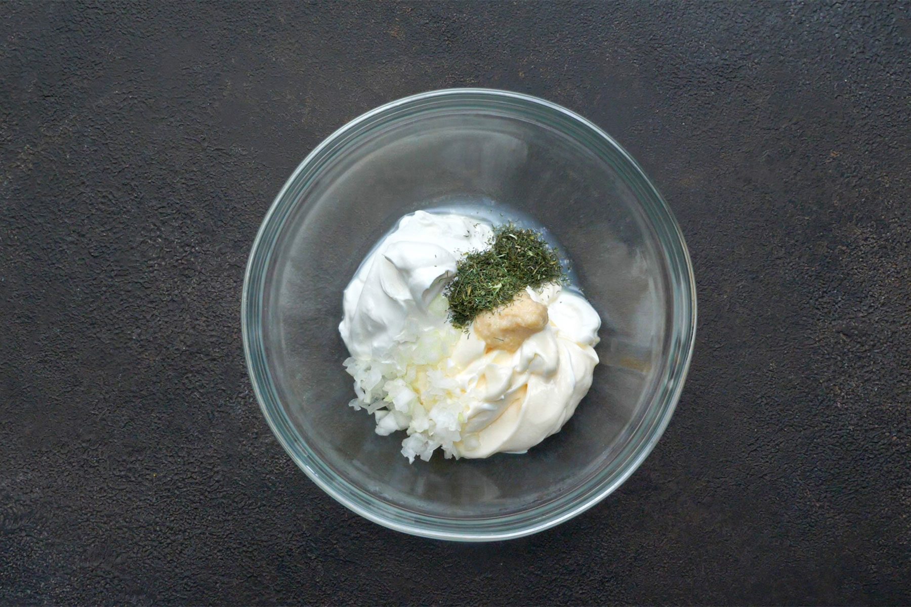 Overhead shot of a bowl; combined the sauce ingredients until smooth; serve with salmon; dark grey background;