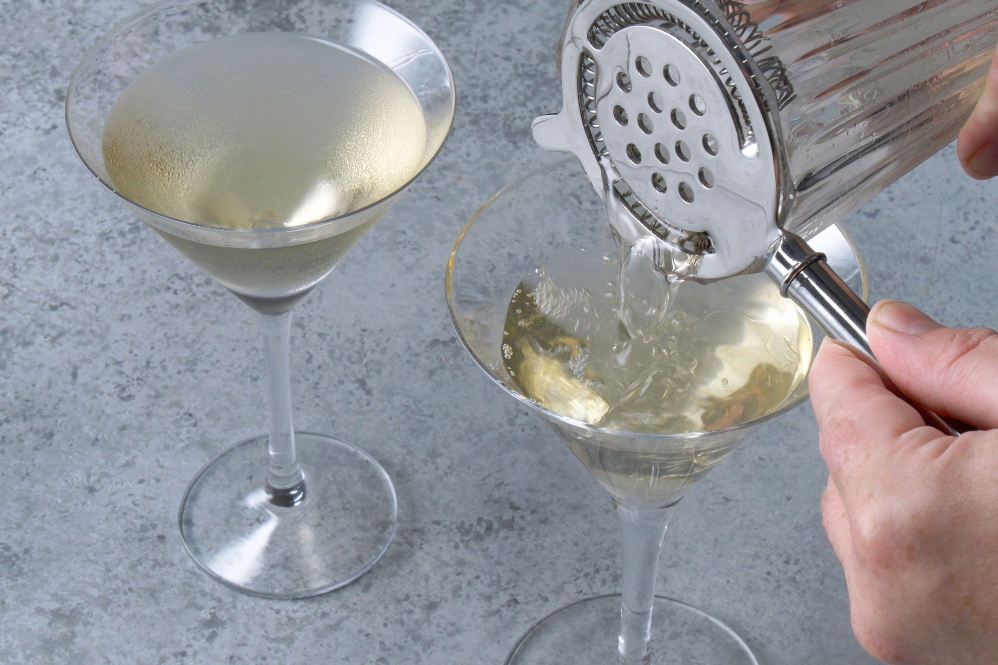 3/4 angle view shot of strain into martini glasses; grey background;