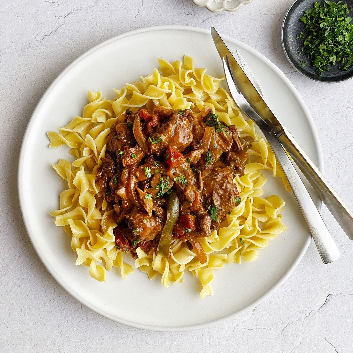 Taste of Home's Round Steak recipe on a bed of egg noodles