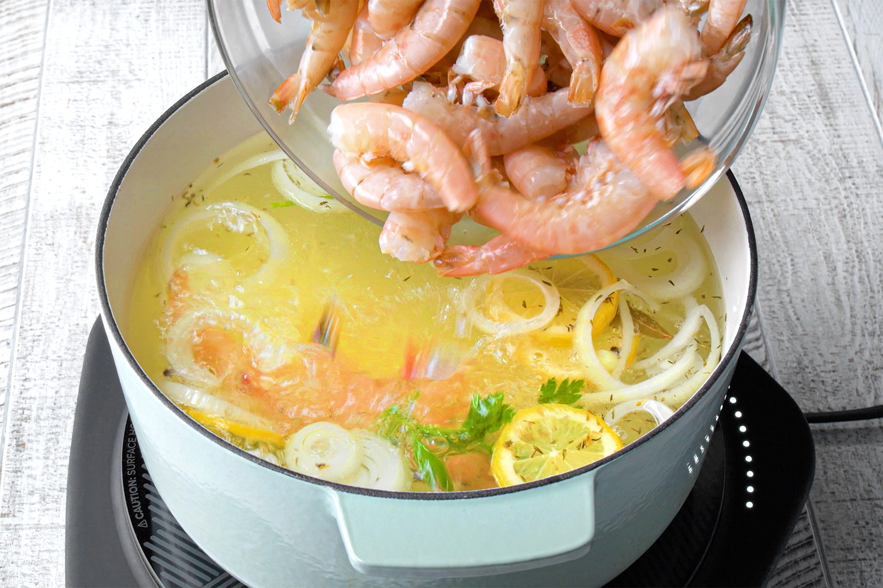 Adding shrimps into the mixture in saucepan