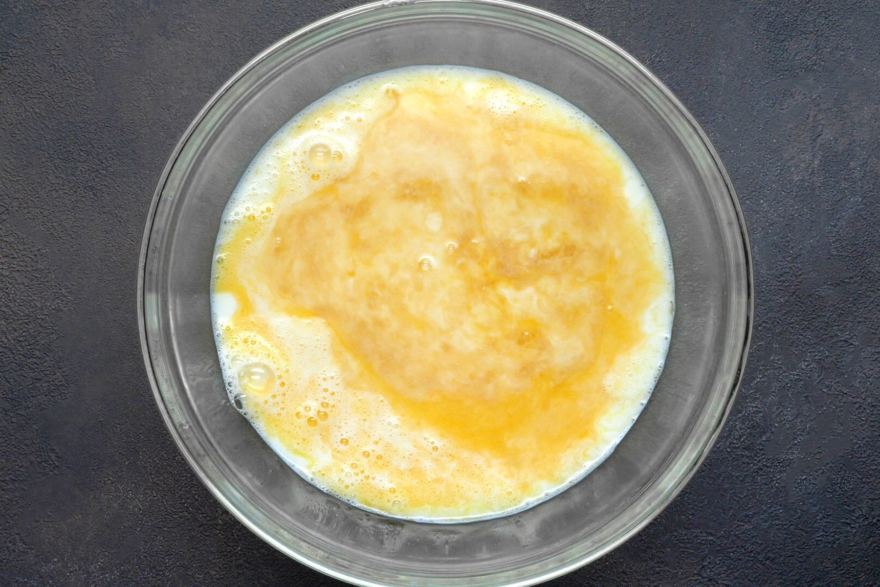 A bowl filled with a mixture of eggs, milk, sugar, vanilla, and salt.