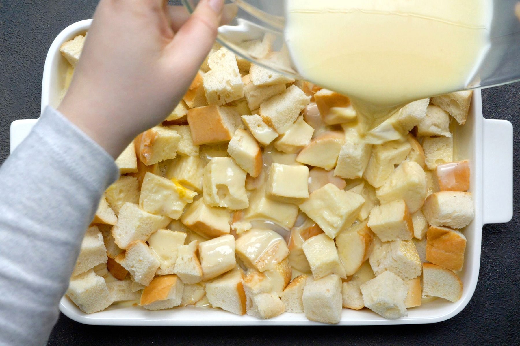 A baking dish filled with French bread cubes topped with butter.