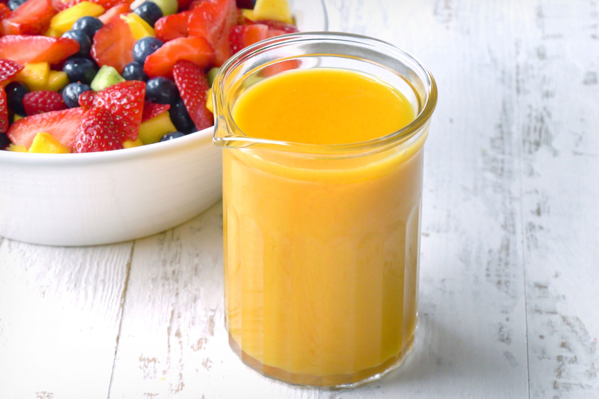 wide shot of fruit salad dressing served with bowl of fruits