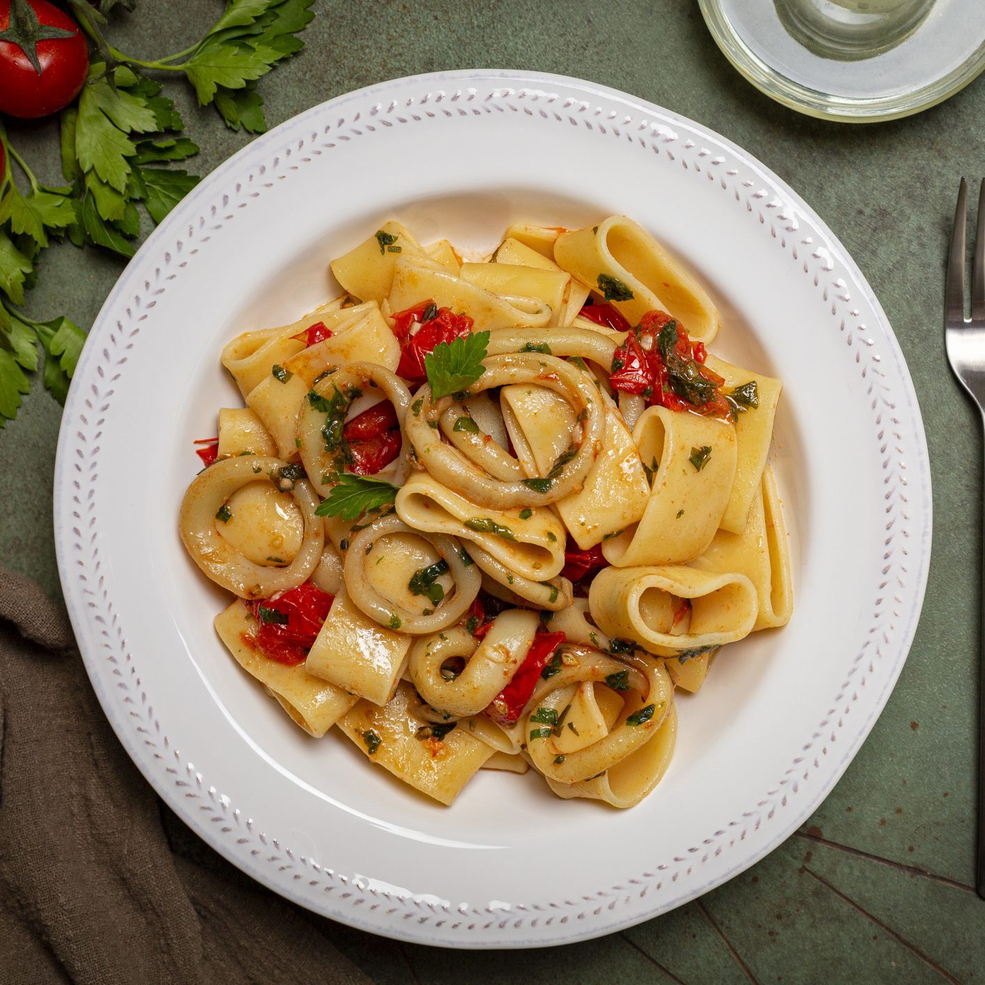 Italian pasta Calamarata made with thick ring pasta paccheri, calamari or sliced squid, and tomato sauce. Originates from Naples, the South of Italy. Directly above.