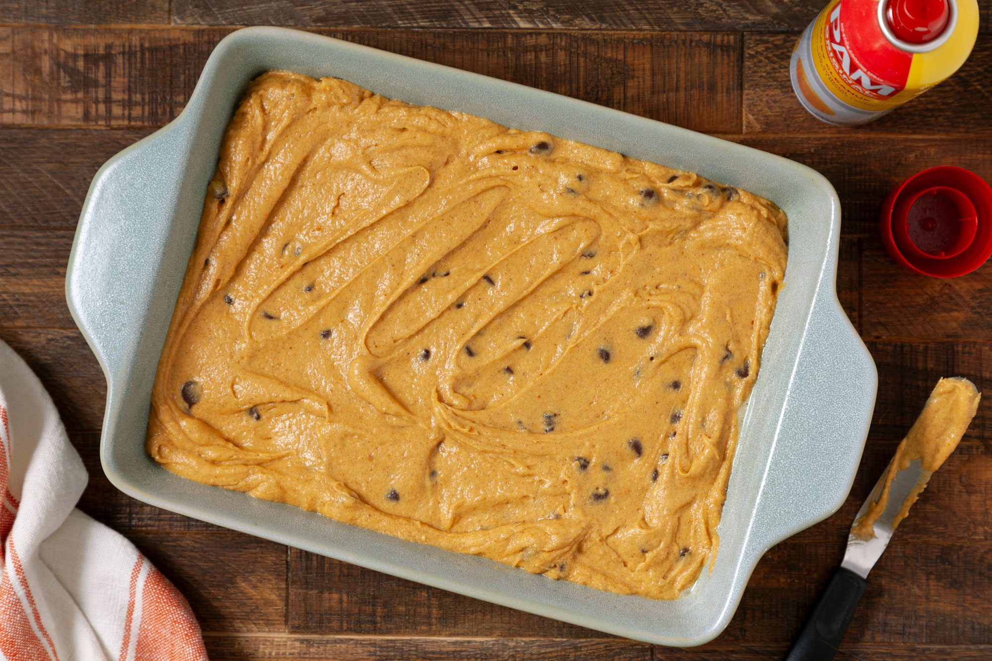 overhead shot of Pumpkin Bars batter in a baking dish on wooden surface