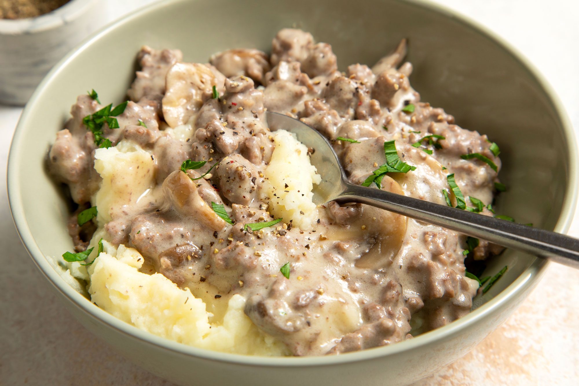 Hamburger Gravy served over mashed potatoes in a bowl with spoon