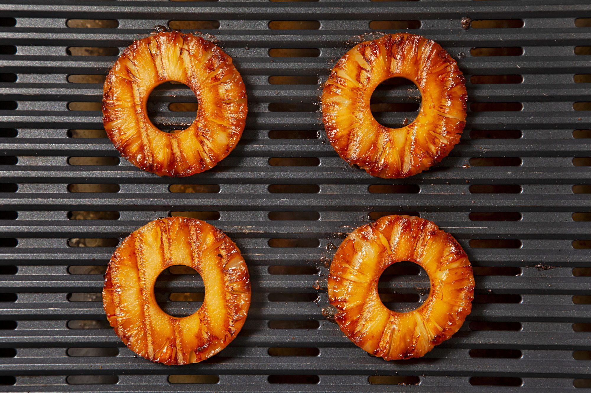 overhead shot; black background; pineapple slices on grill;