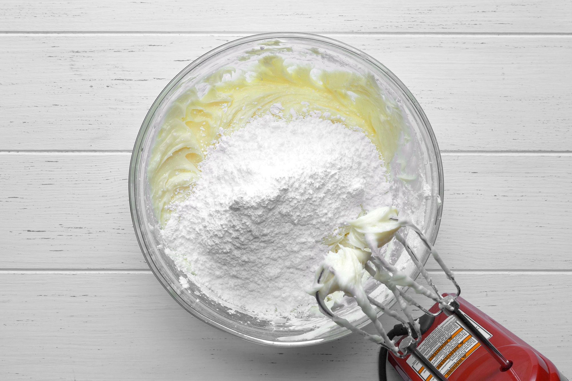 Overhead shot of blend ingredients in a large bowl; blending machine; white wooden background;