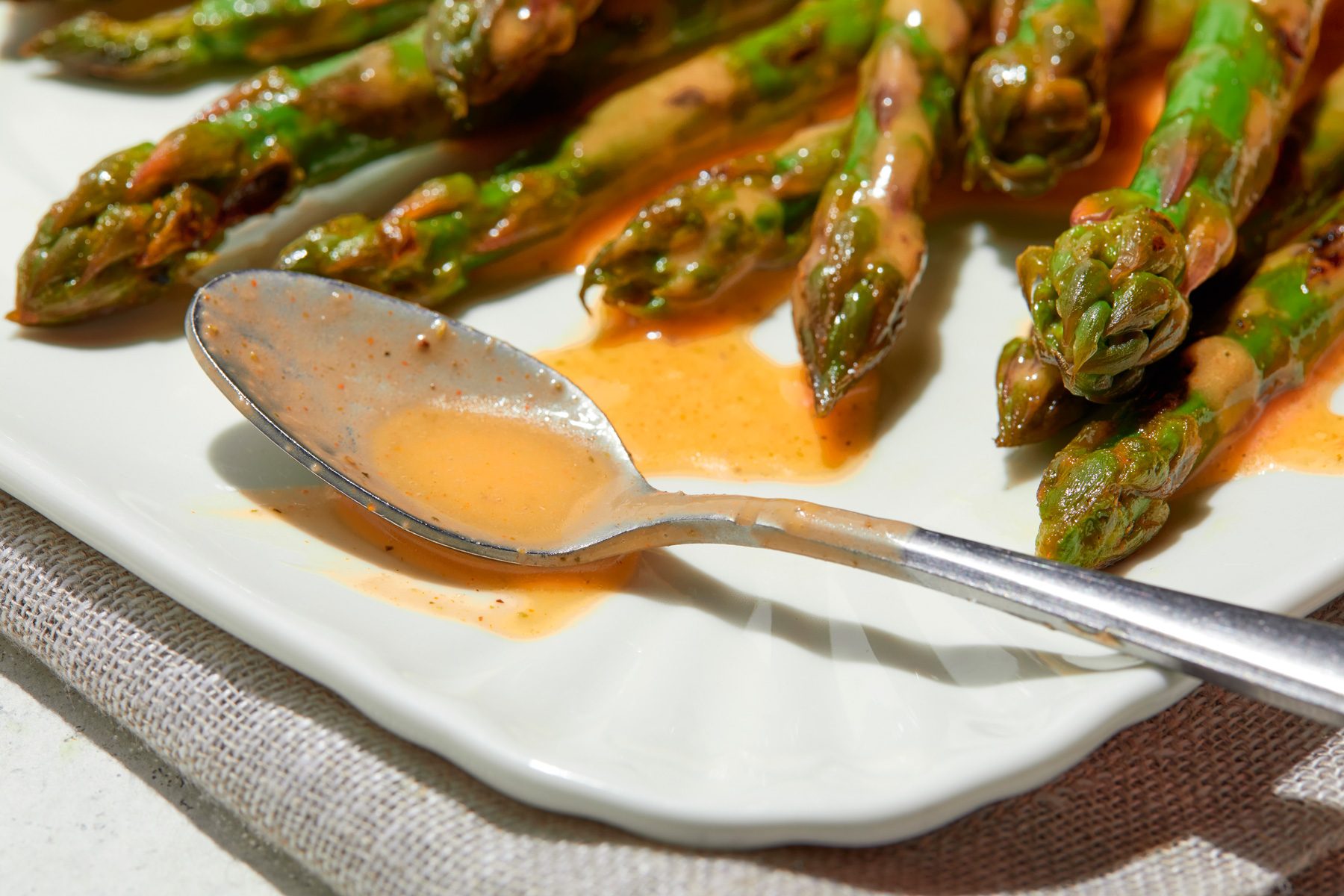 A plate of asparagus with Italian Dressing drizzled on top