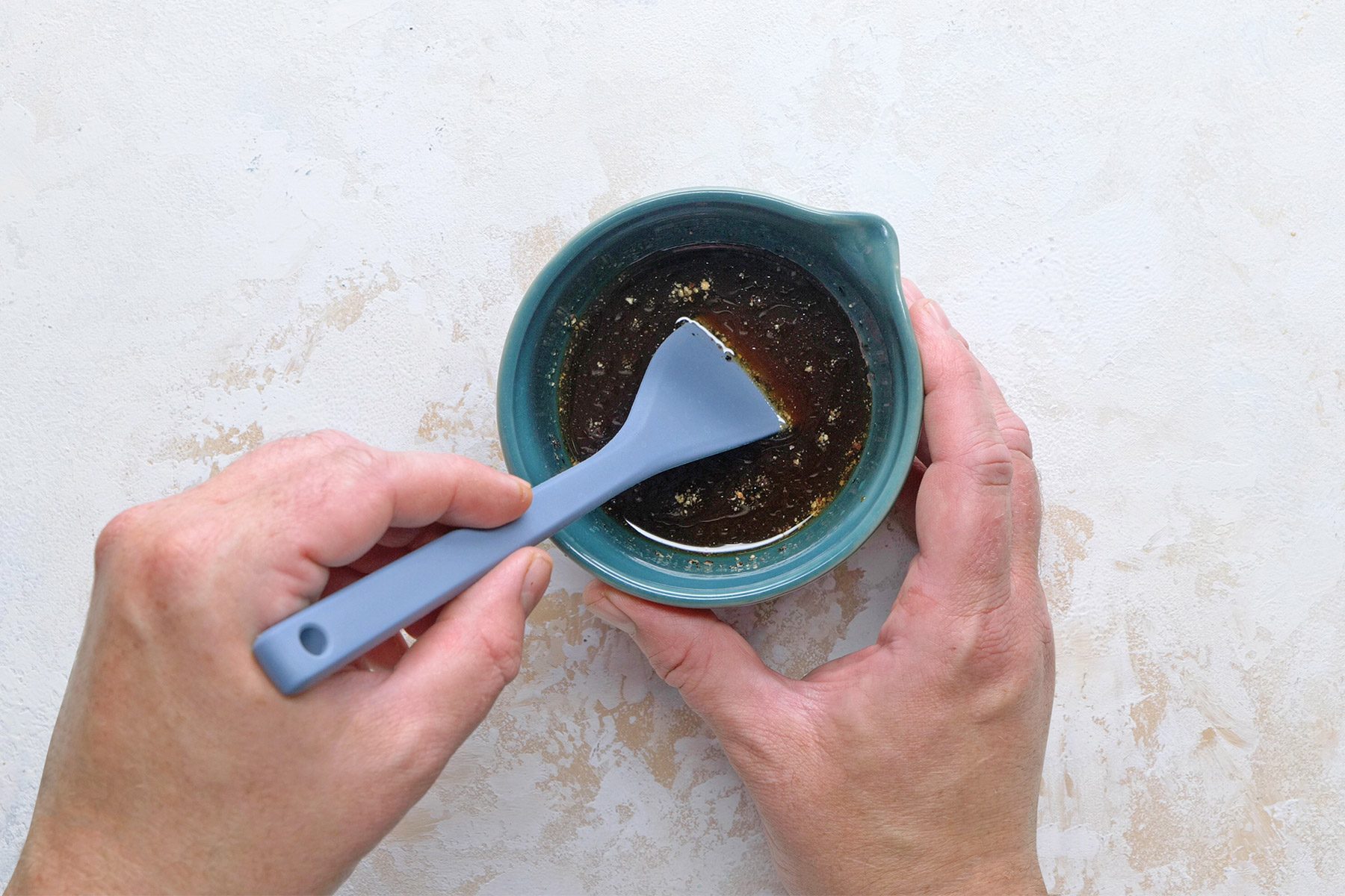 Overhead shot of a small bowl; for sauce combine Shaoxing wine; soy sauce; sugar; vinegar; oyster sauce; hoisin sauce; sesame oil and pepper; marble background