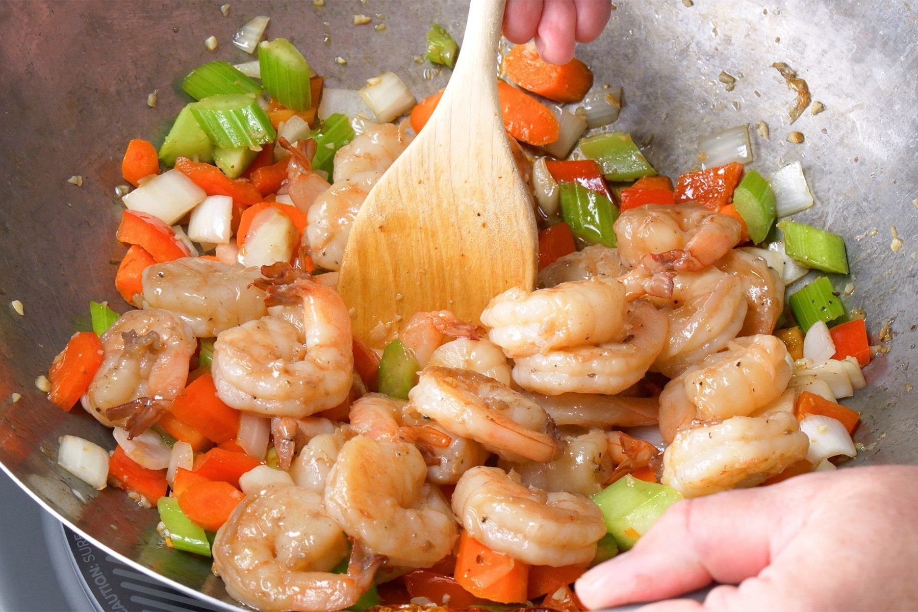 Close shot of add sauce and shrimp in the same skillet; cook and stir until shrimp turn pink and sauce is slightly thickened; induction; marble background