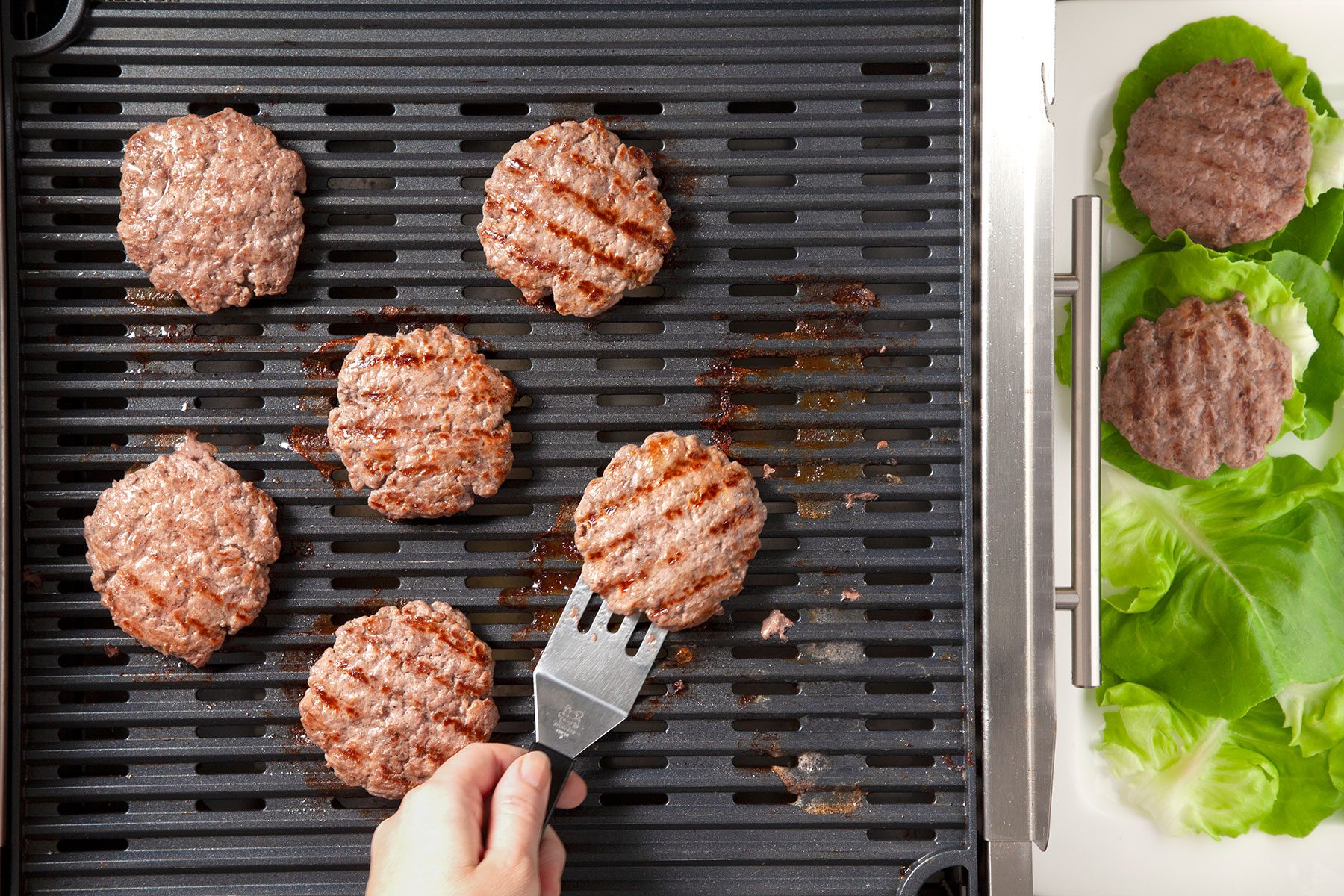 Overheads hot of grill burgers; covered; over medium heat; place burgers in lettuce leaves; griller; white large tray;