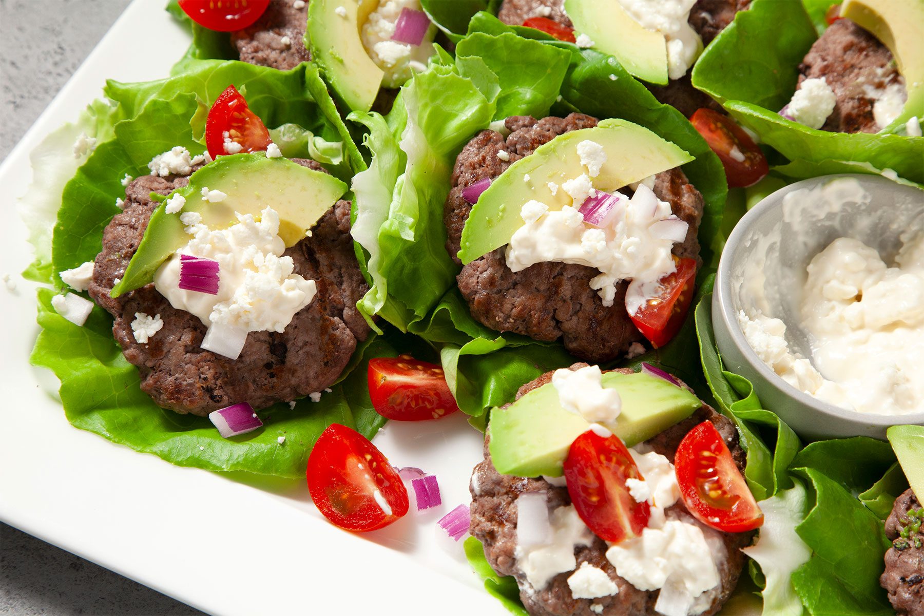 Close shot of Calofornia Burger Wraps; on white large tray; with feta and miracle whip; grey marble background;