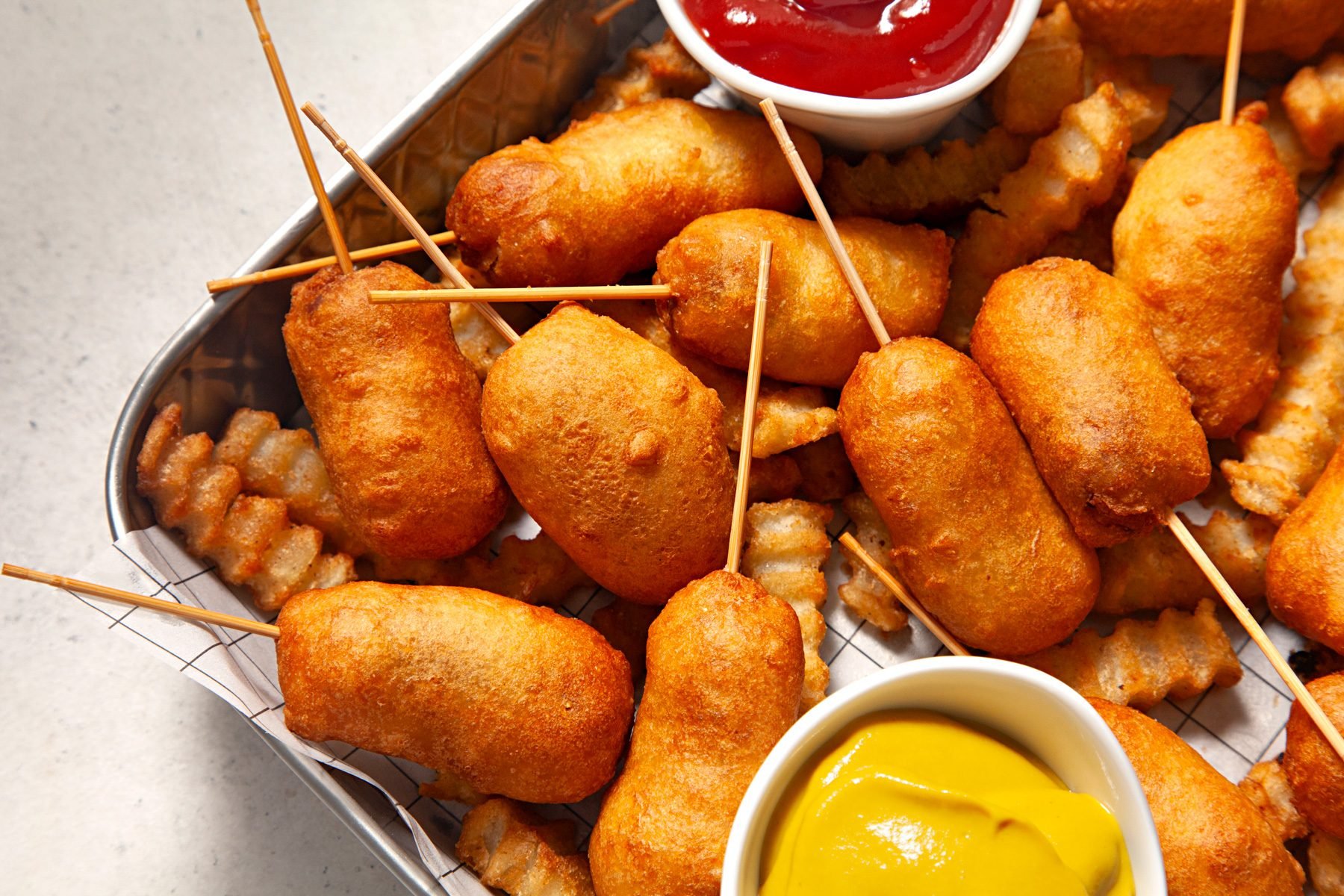 A tray of miniature corn dogs served with sauce