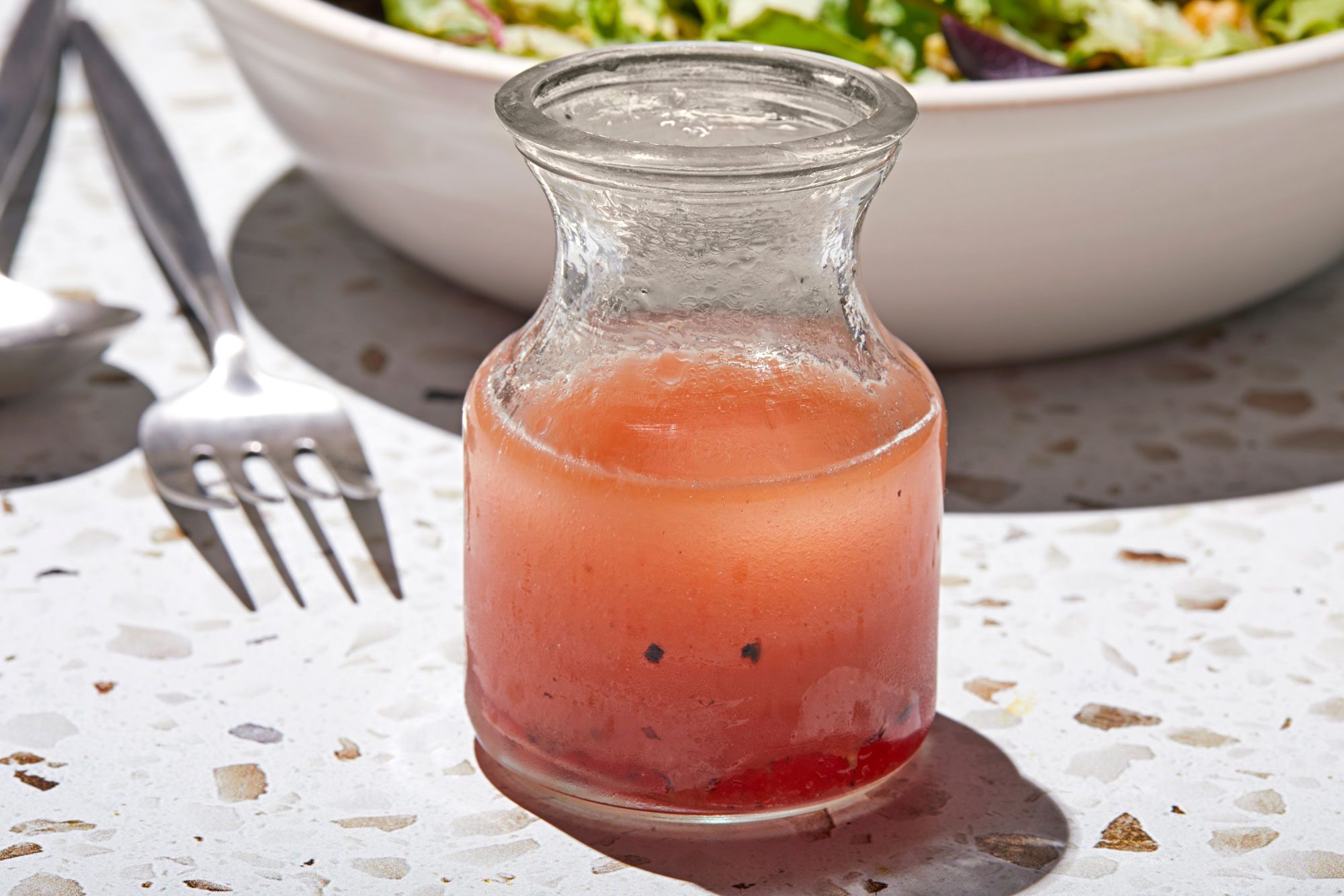 Oil and Vinegar Dressing in a small jar with salad, spoon and fork