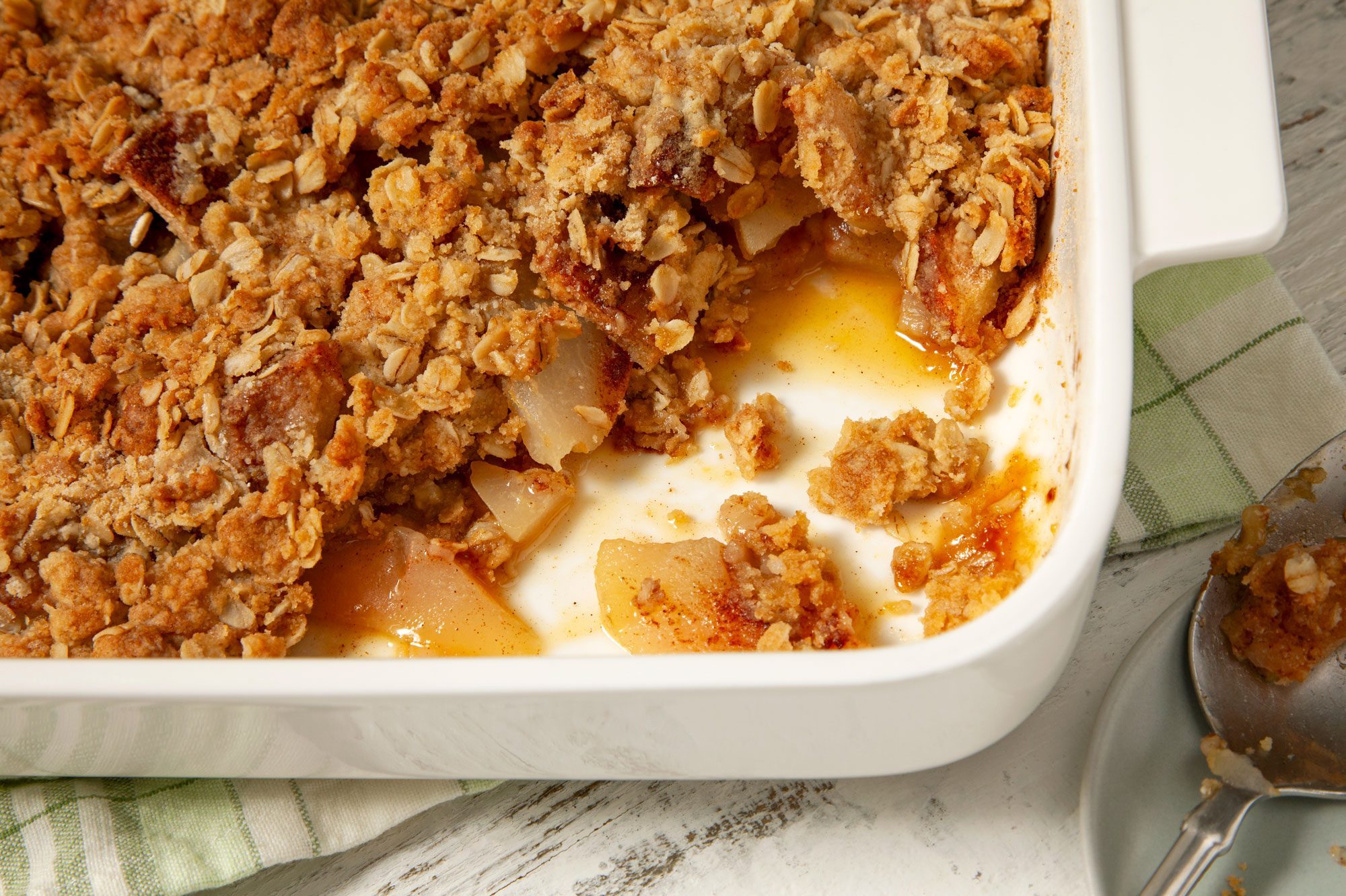 Pear Crisp in a baking dish with napkin and serving spoon in a small plate