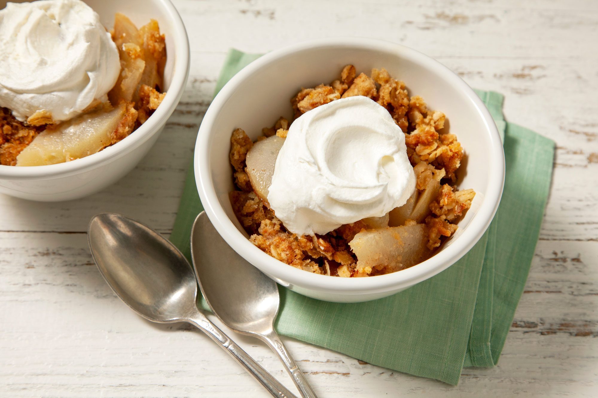 Pear Crisp served in two bowls topped with ice cream spoons