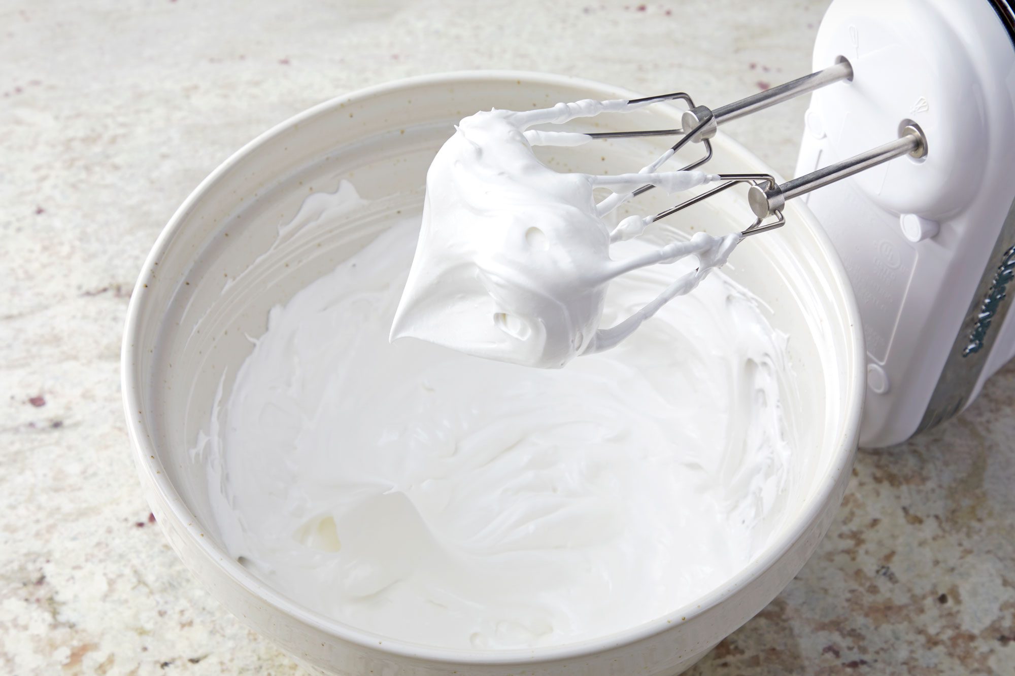 3/4th shot; white textured background; In a small bowl, beating the cream cheese, butter, confectioners' sugar and vanilla until smooth with electric whisker;