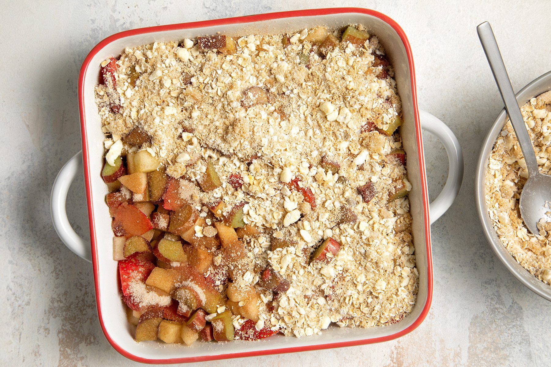 overhead shot of oat mix spread over rhubarb mixture in a dutch oven