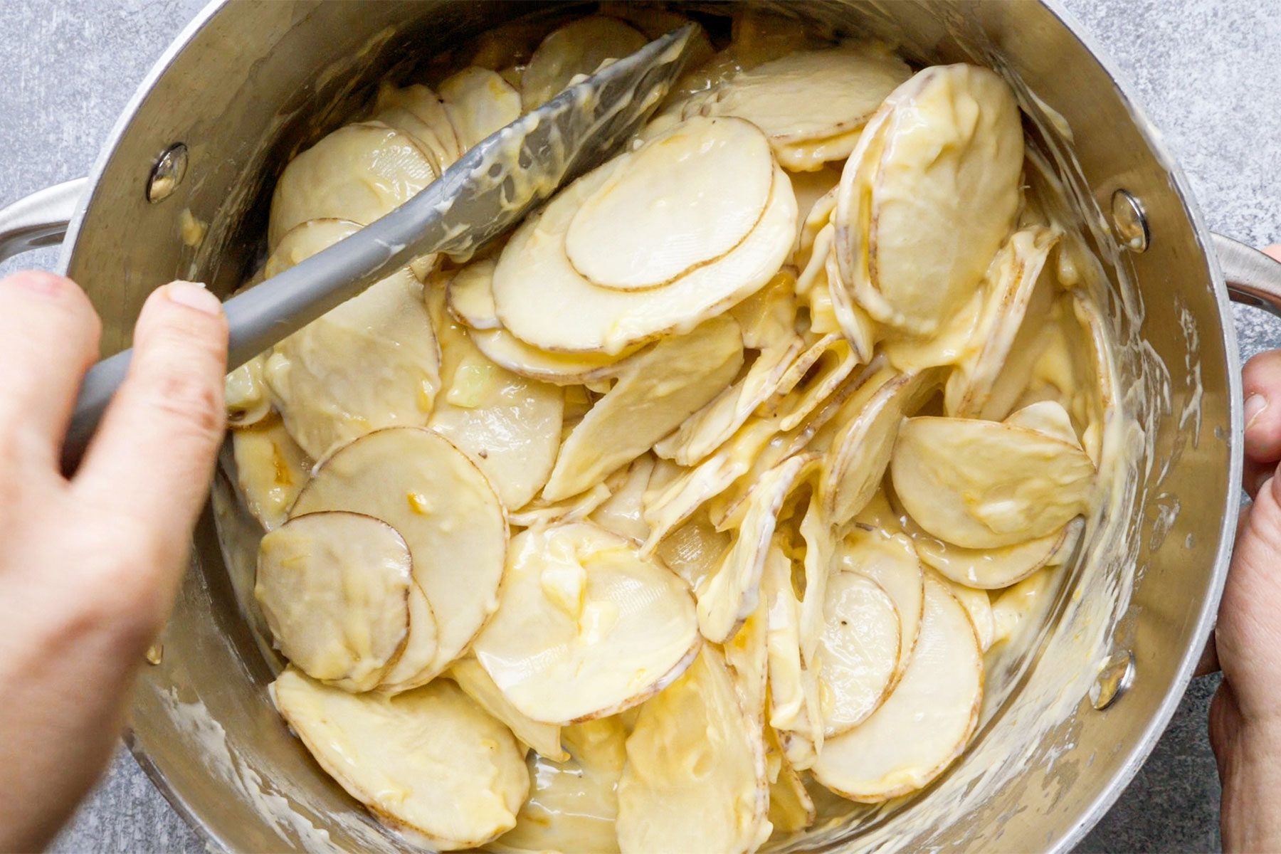 overhead shot of sliced potato added in the cheese mix in a large saucepan