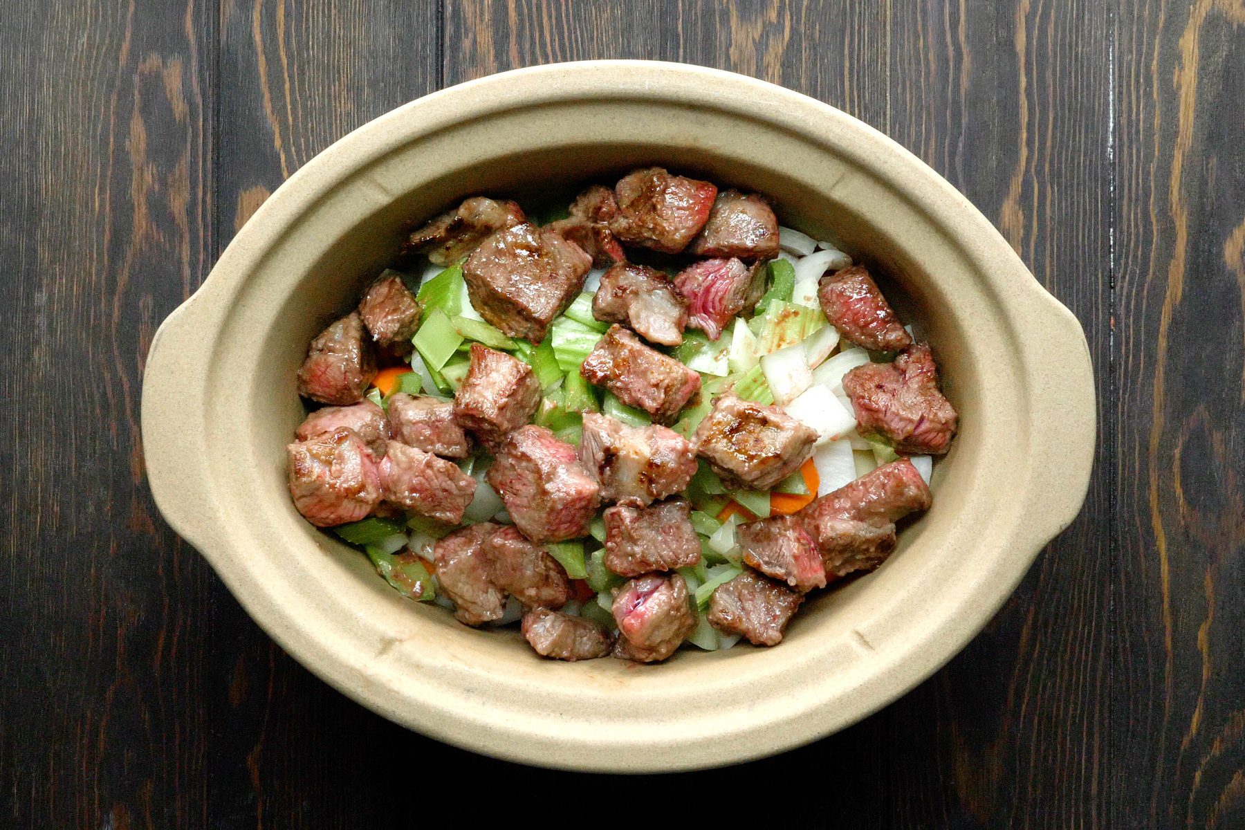 A slow cooker filled with meat and vegetables.