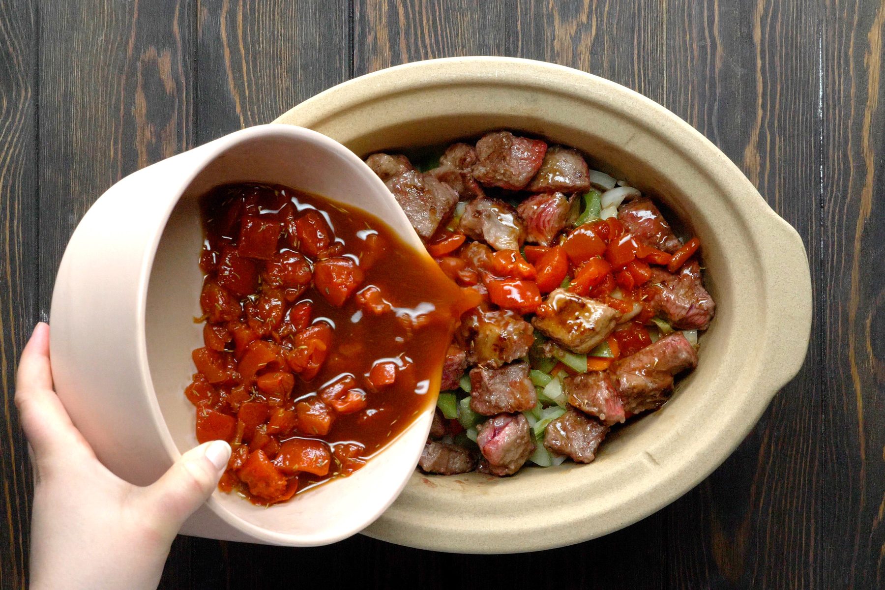 A hand pouring the liquid over the beef.