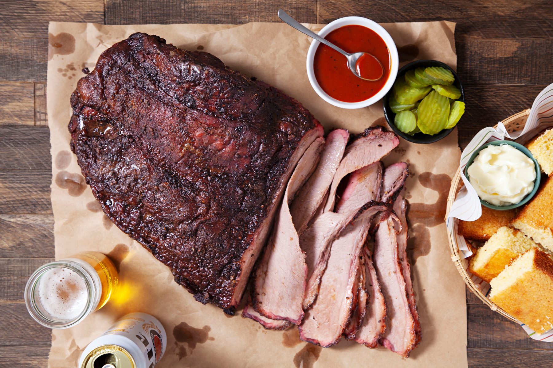 Sliced smoked brisket with sauce on a table.