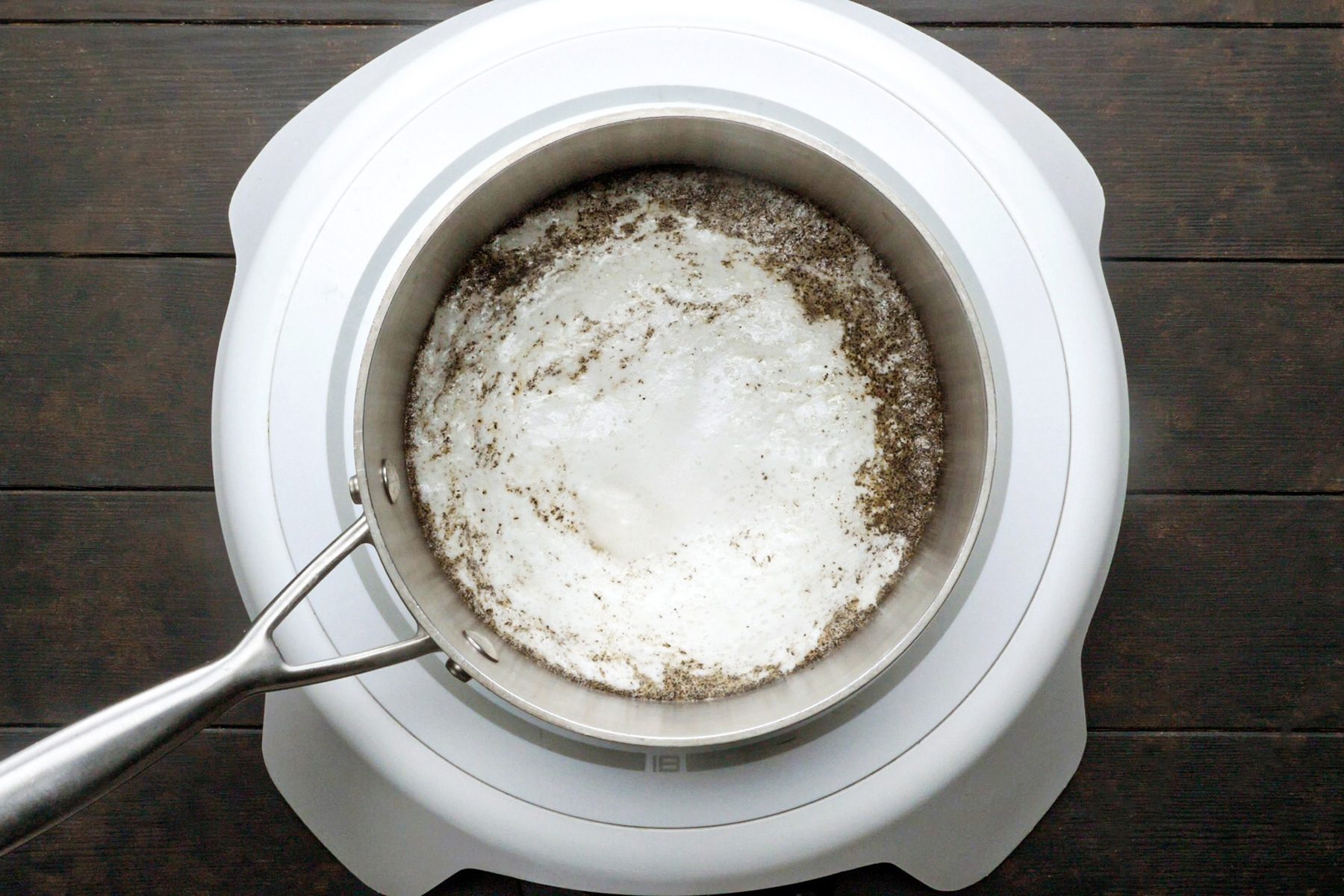 A mixture of broth, milk, butter, salt and pepper boiling in a saucepan