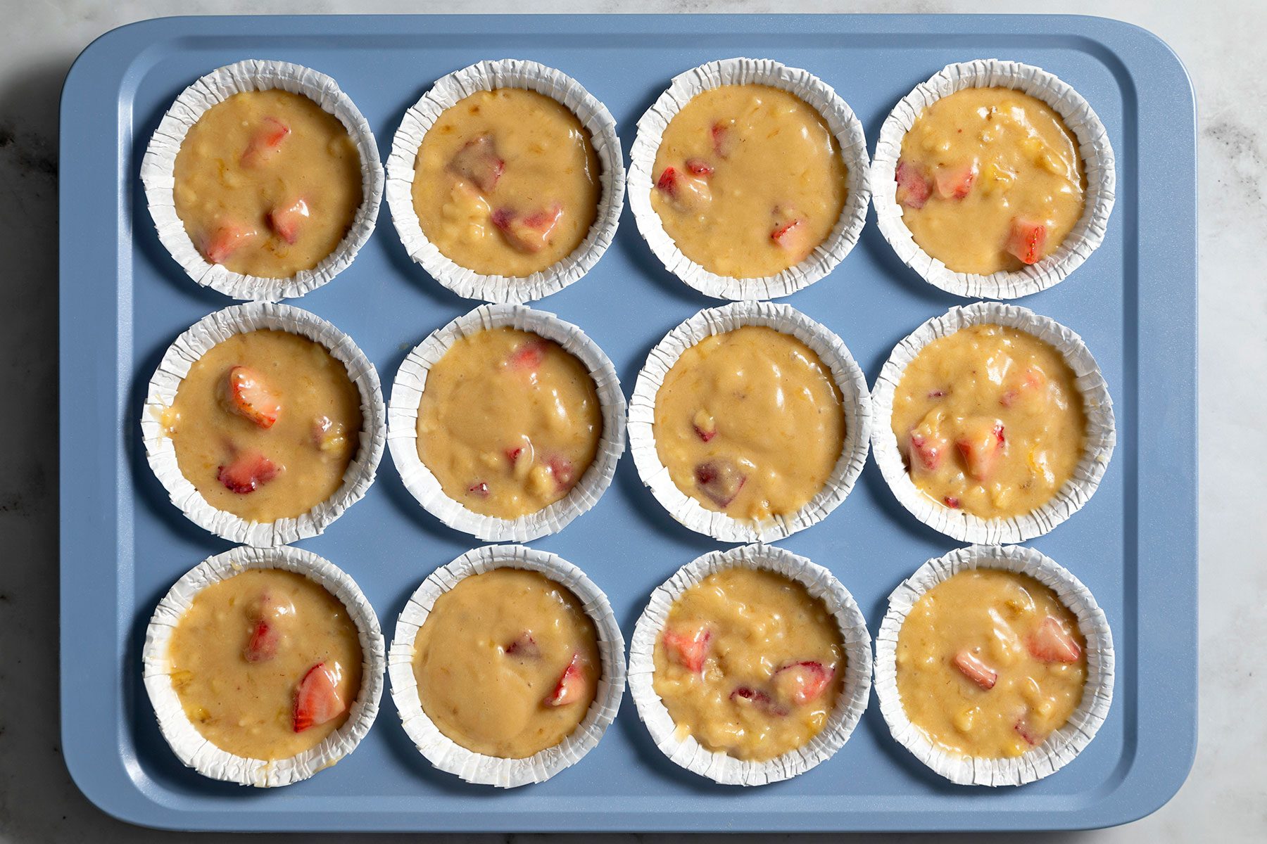 overhead shot of strawbeery banana muffin batter in the cups