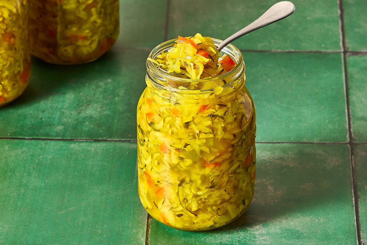 Closeup of sweet zucchini relish in an open jar with a spoon
