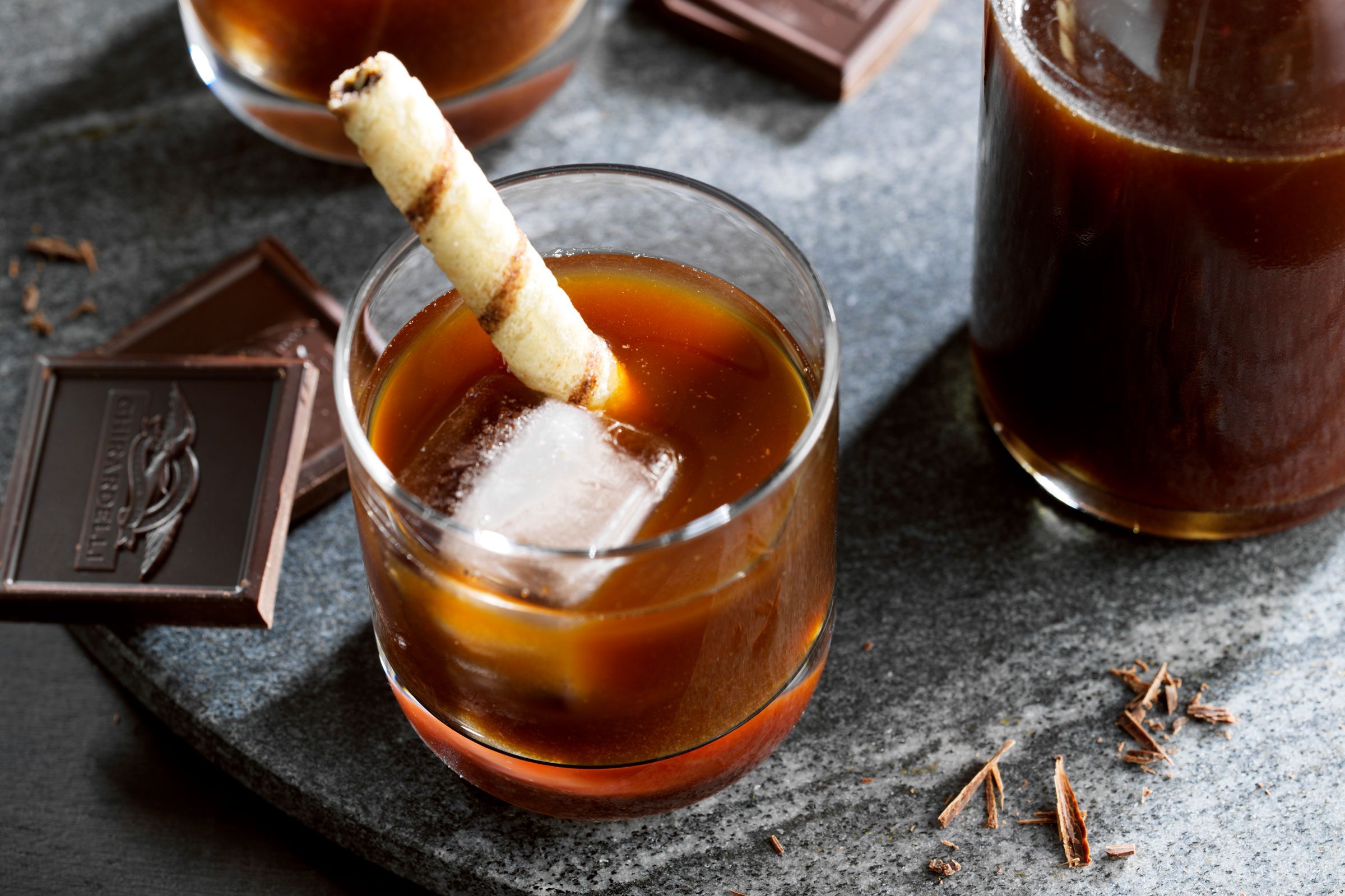 Chocolate Liqueur in a glass with a pirouette cookie in the drink and chocolate squares next to the glass