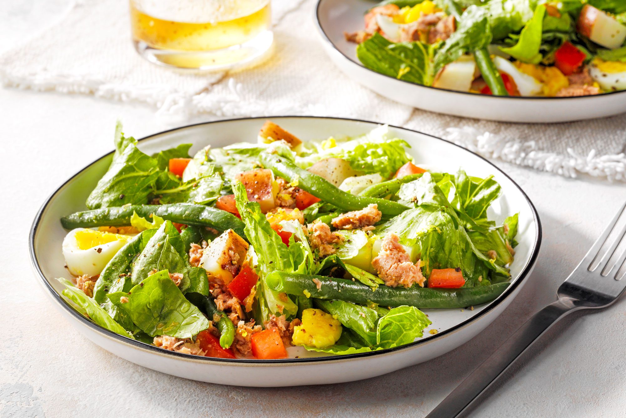 Vibrant Tuna Nicoise salad includes tuna, mixed greens, cherry tomatoes, olives, eggs, and green beans