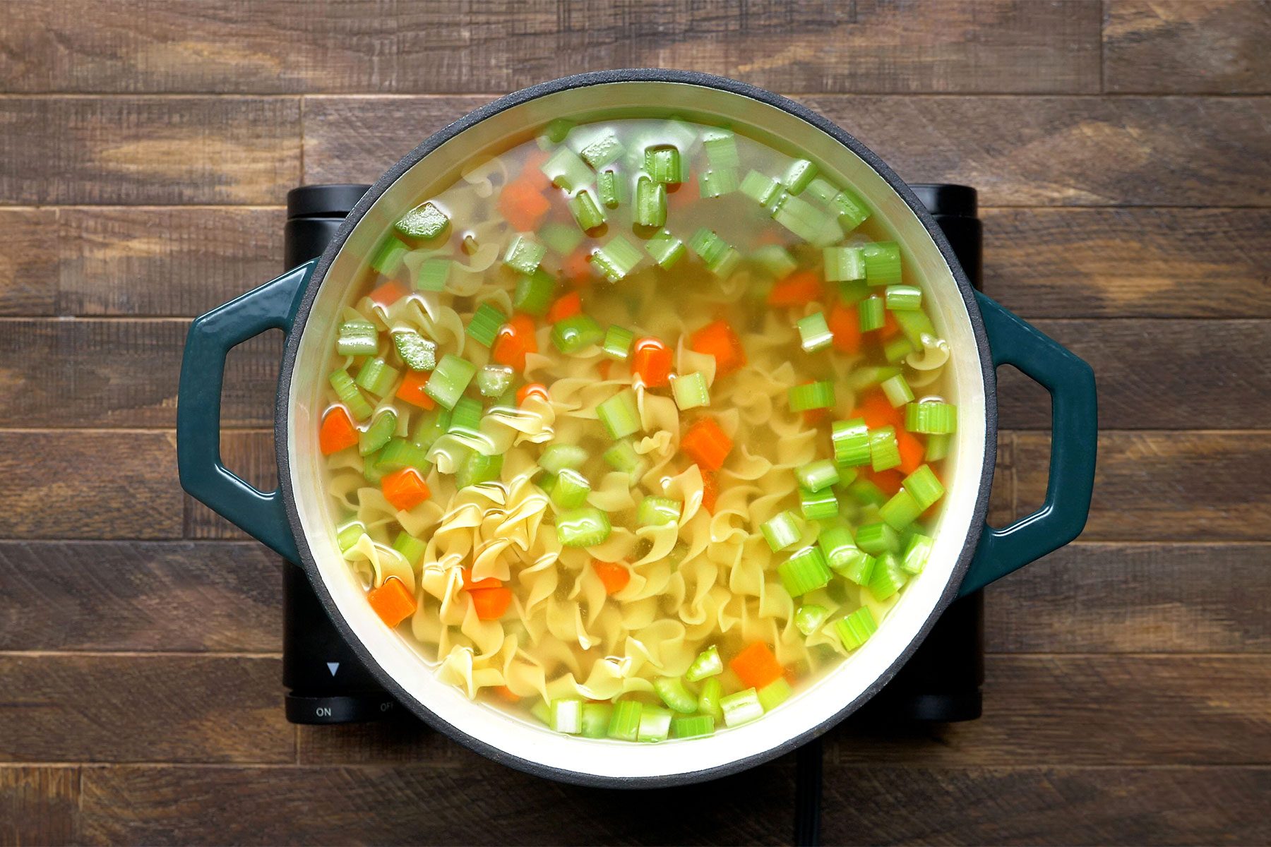 overhead shot of carrots and noodles in a dutch oven