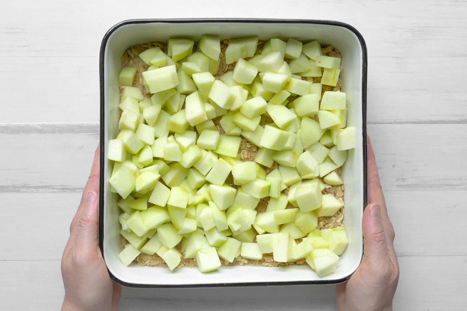A square baking dish filled with chopped apples.