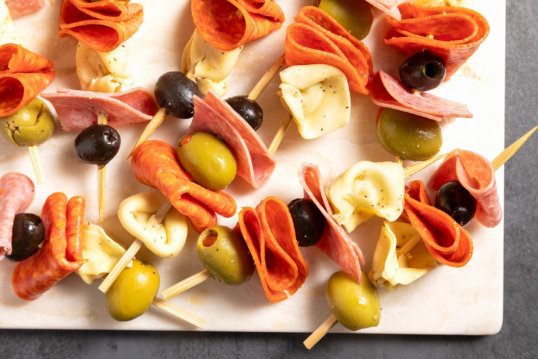 overhead shot; grey textured background; Antipasto Kabobs placed over wooden board
