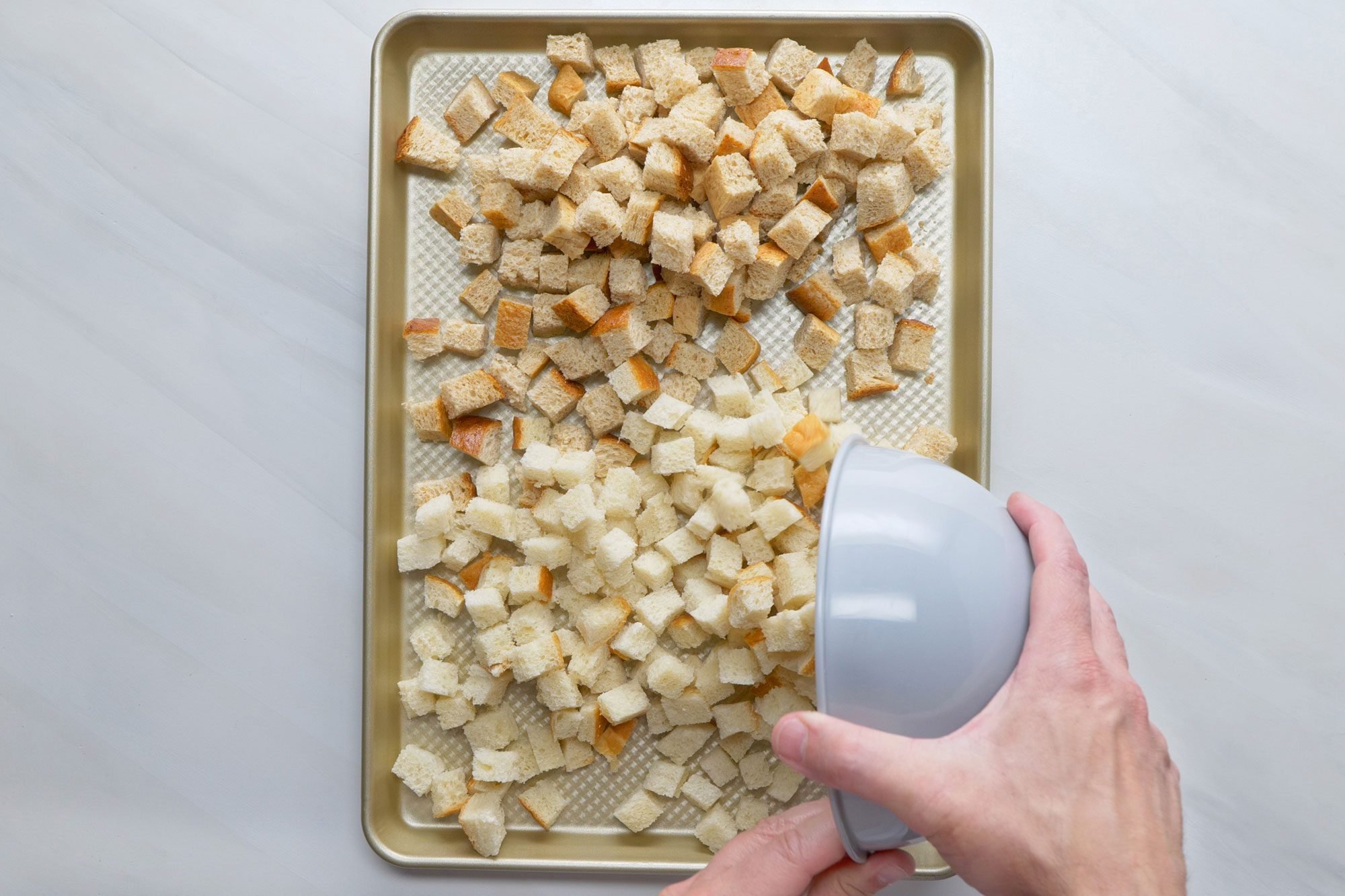 overhead shot; white background; Placed bread cubes on ungreased baking sheet in a baking tray;