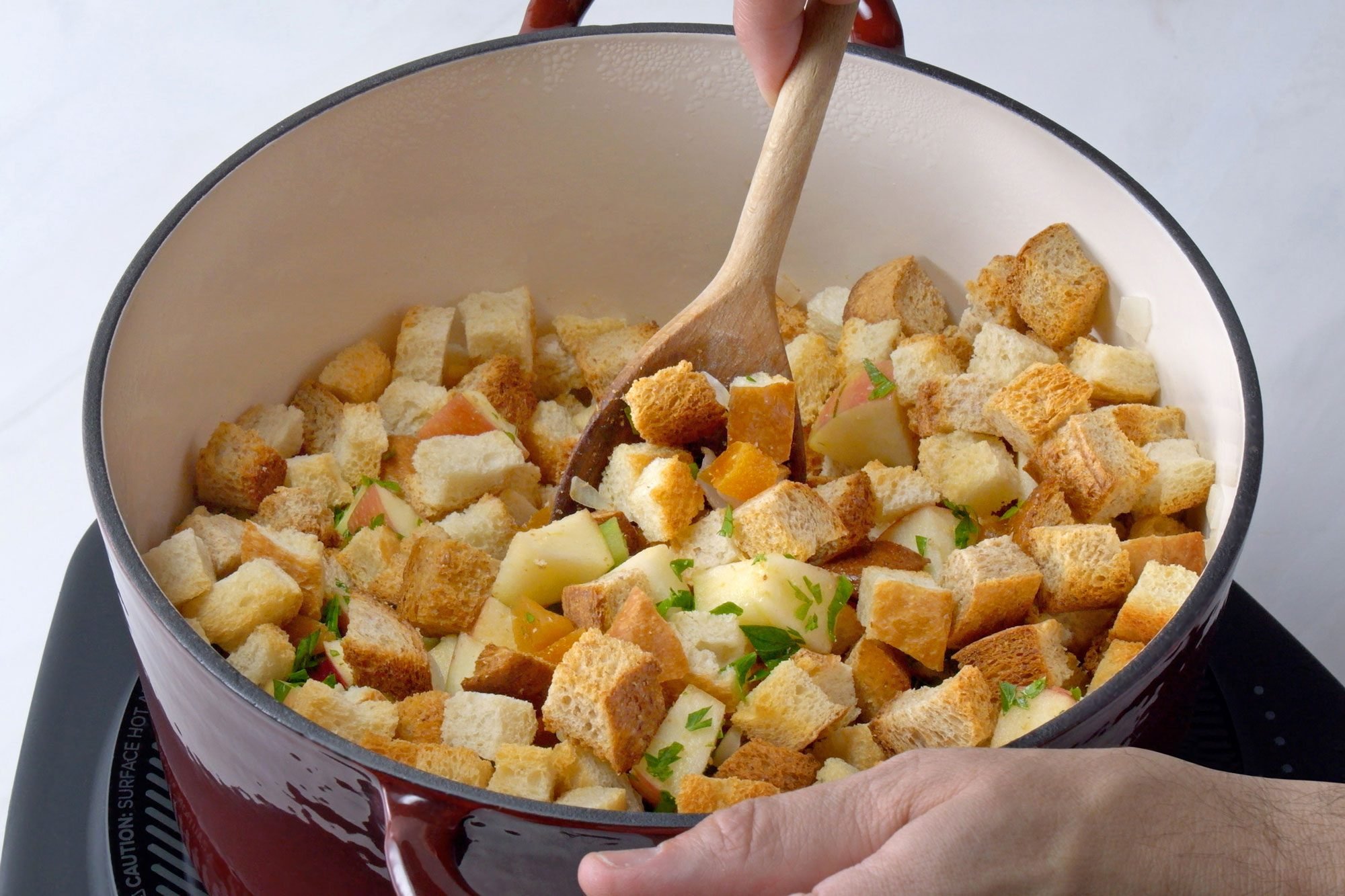 3/4th shot; white background; In a Dutch oven, Added bread cubes with celery and onion and cooking and stiring with wooden spatula;