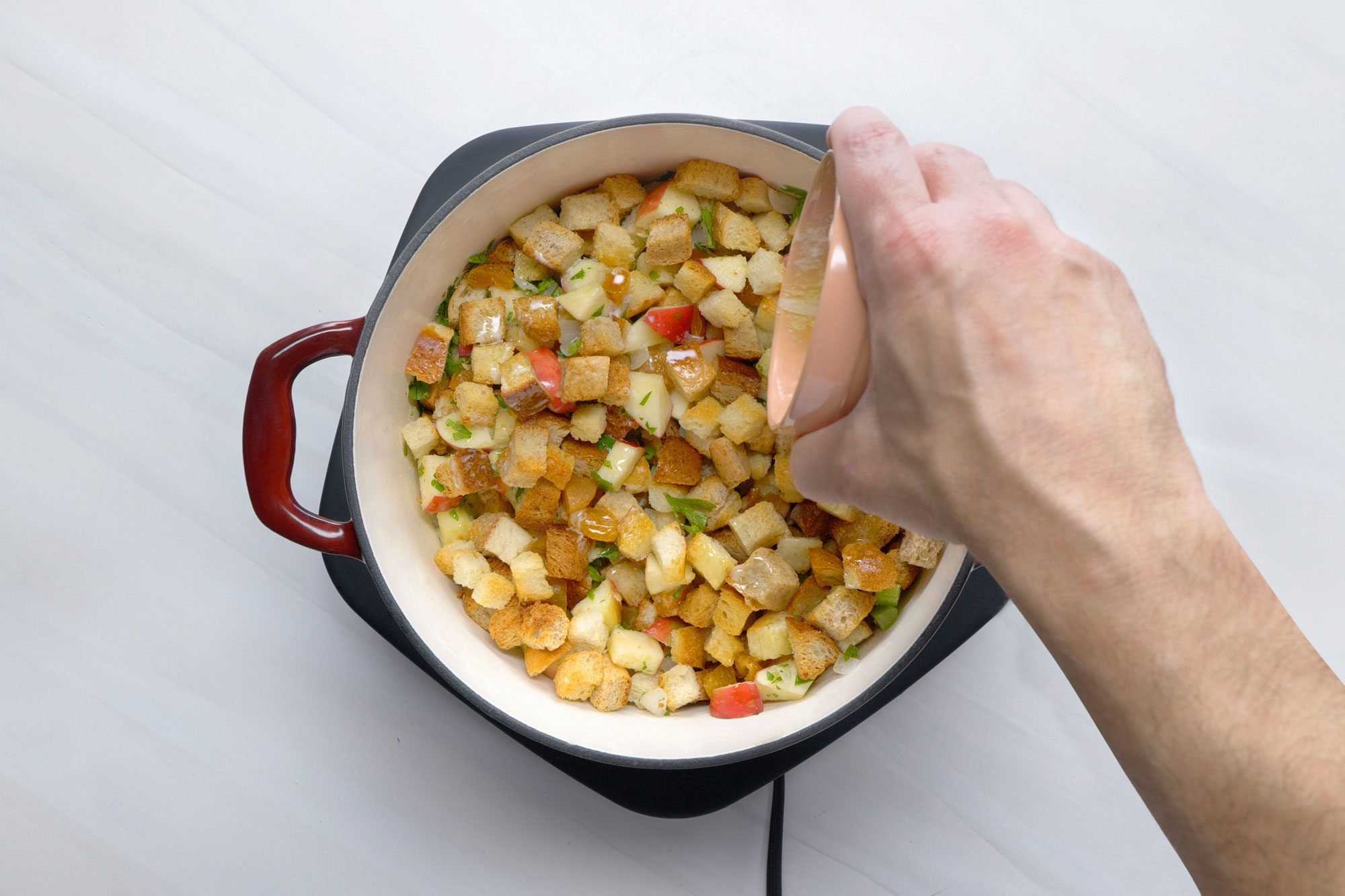 overhead shot; white background; added broth and melted butter over bread cubes in dutch oven;