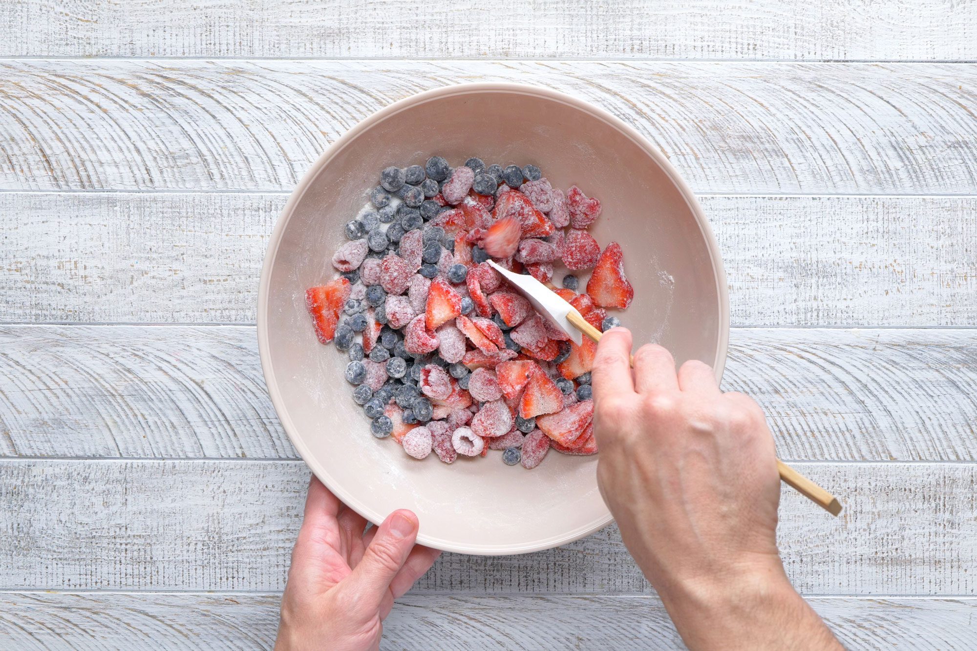 overhead shot; white textured background; In a large bowl, combining the berries, sugar and flour;