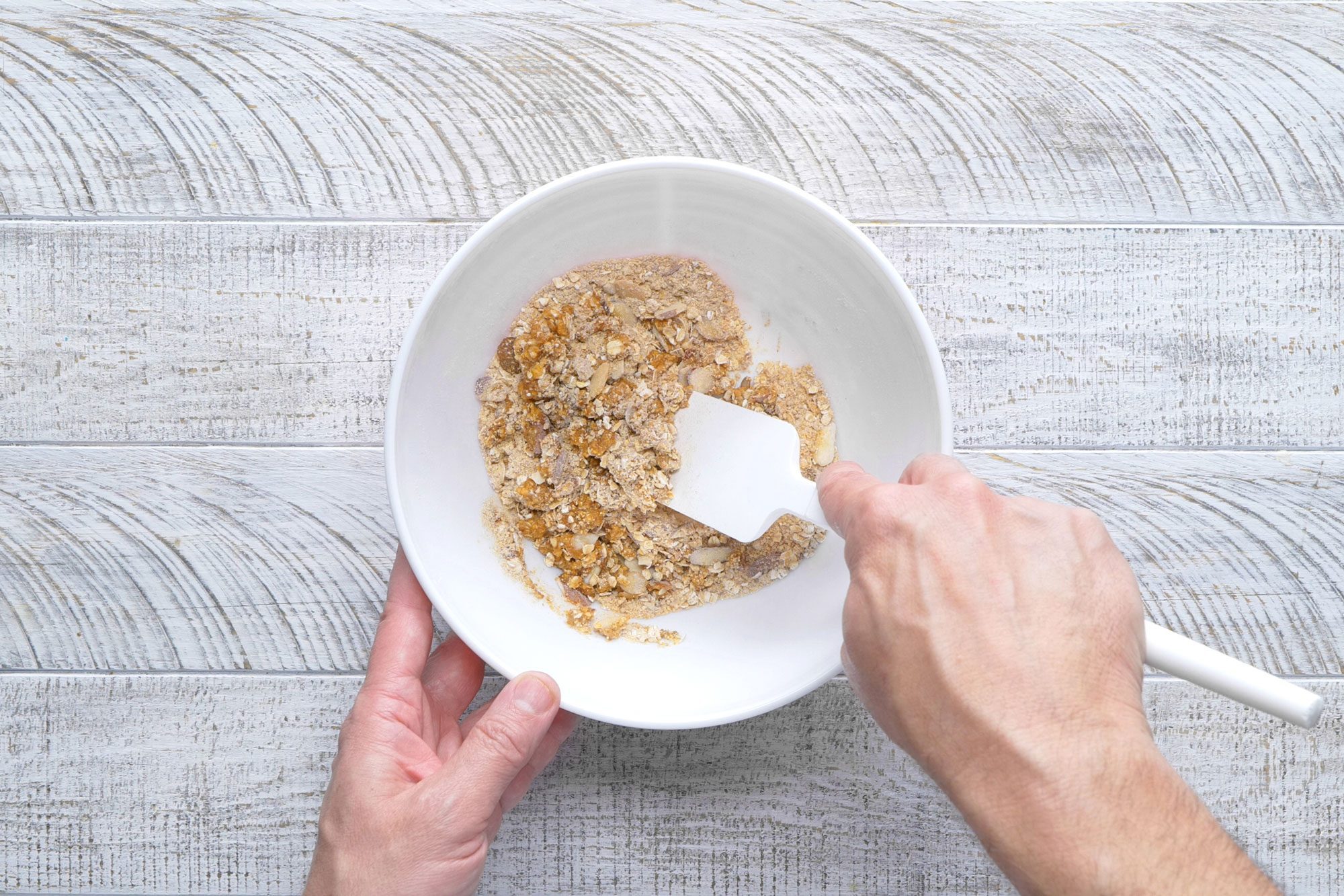 overhead shot; white textured background; In a small bowl, combining the cracker crumbs, oats, brown sugar, almonds, cinnamon and remaining flour;