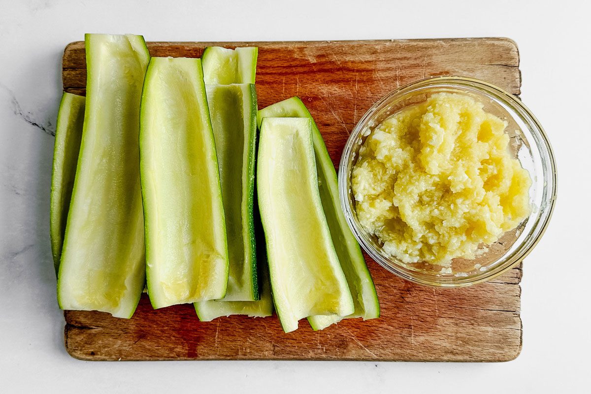 Scooped zucchini halves next to a bowl of zucchini pulp for Taste of Home Buffalo Chicken Zucchini Boats.