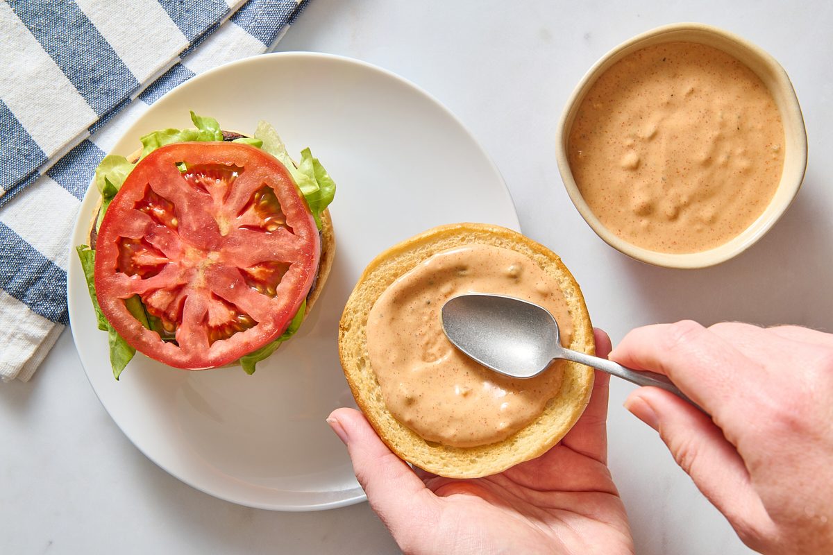 Spreading burger sauce onto a burger bun